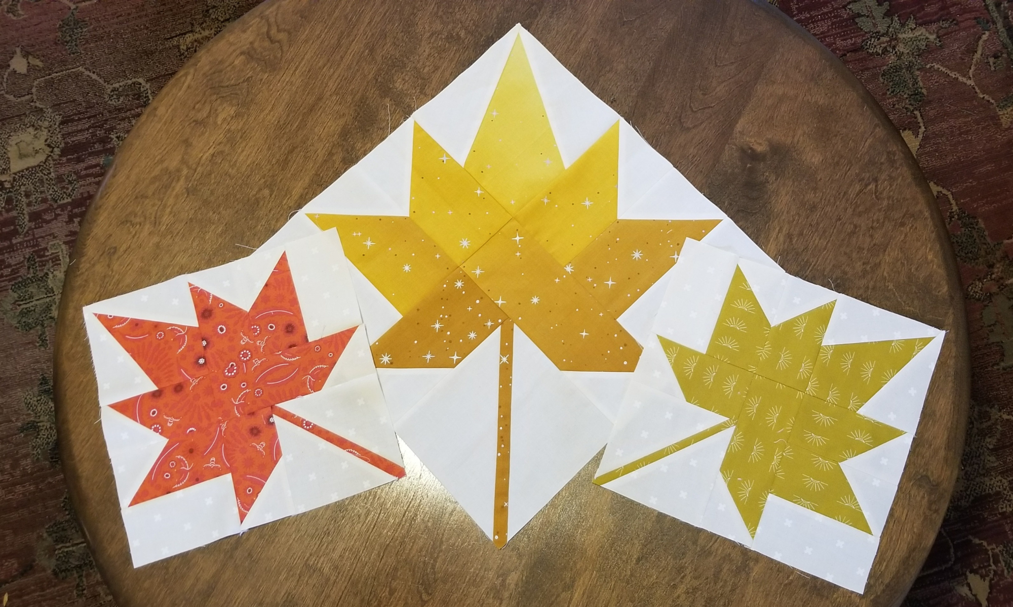 three autumn leaf blocks on a wooden circle